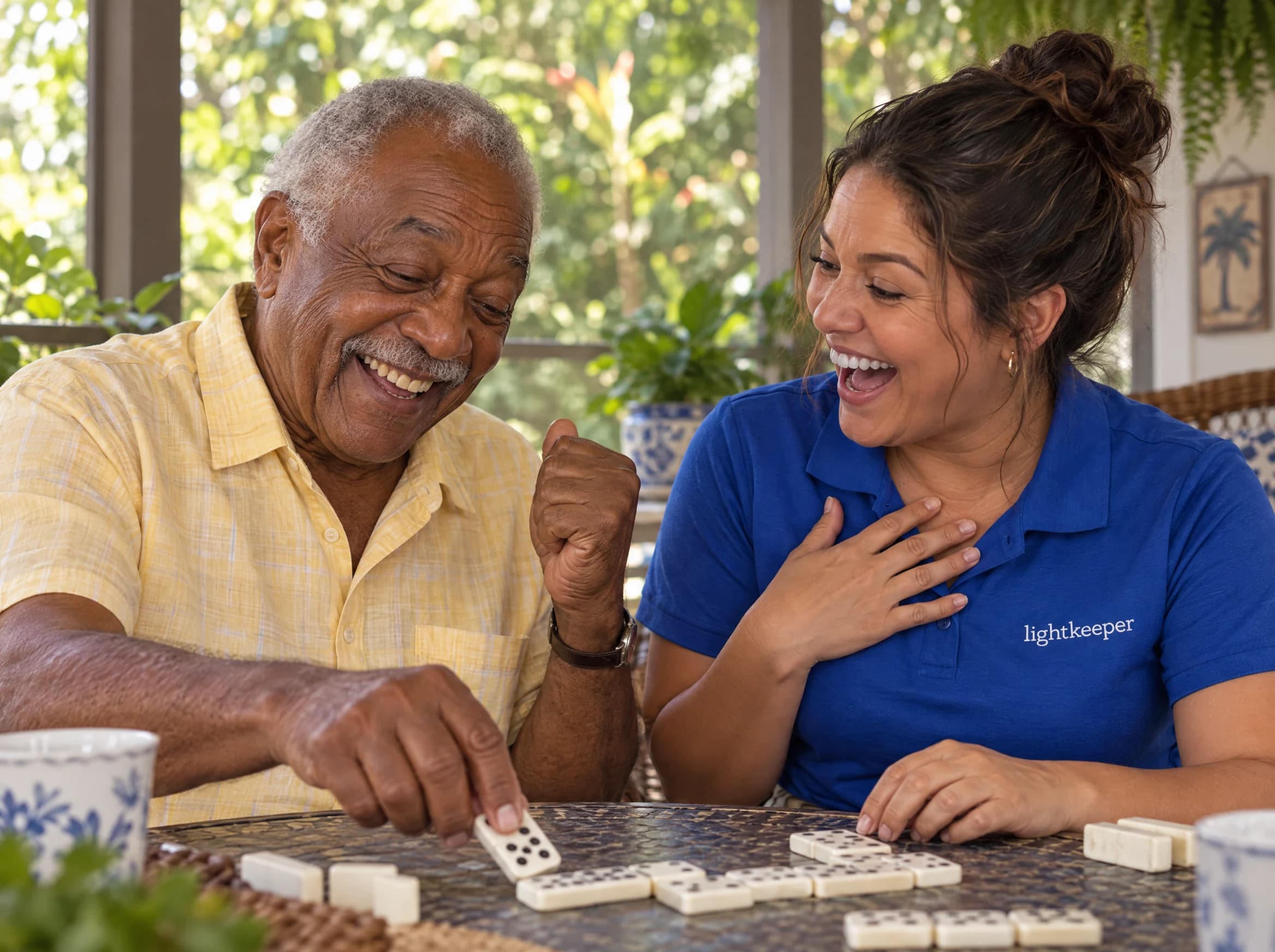 An older man and his Lightkeeper share a laugh over a game of dominoes on his porch