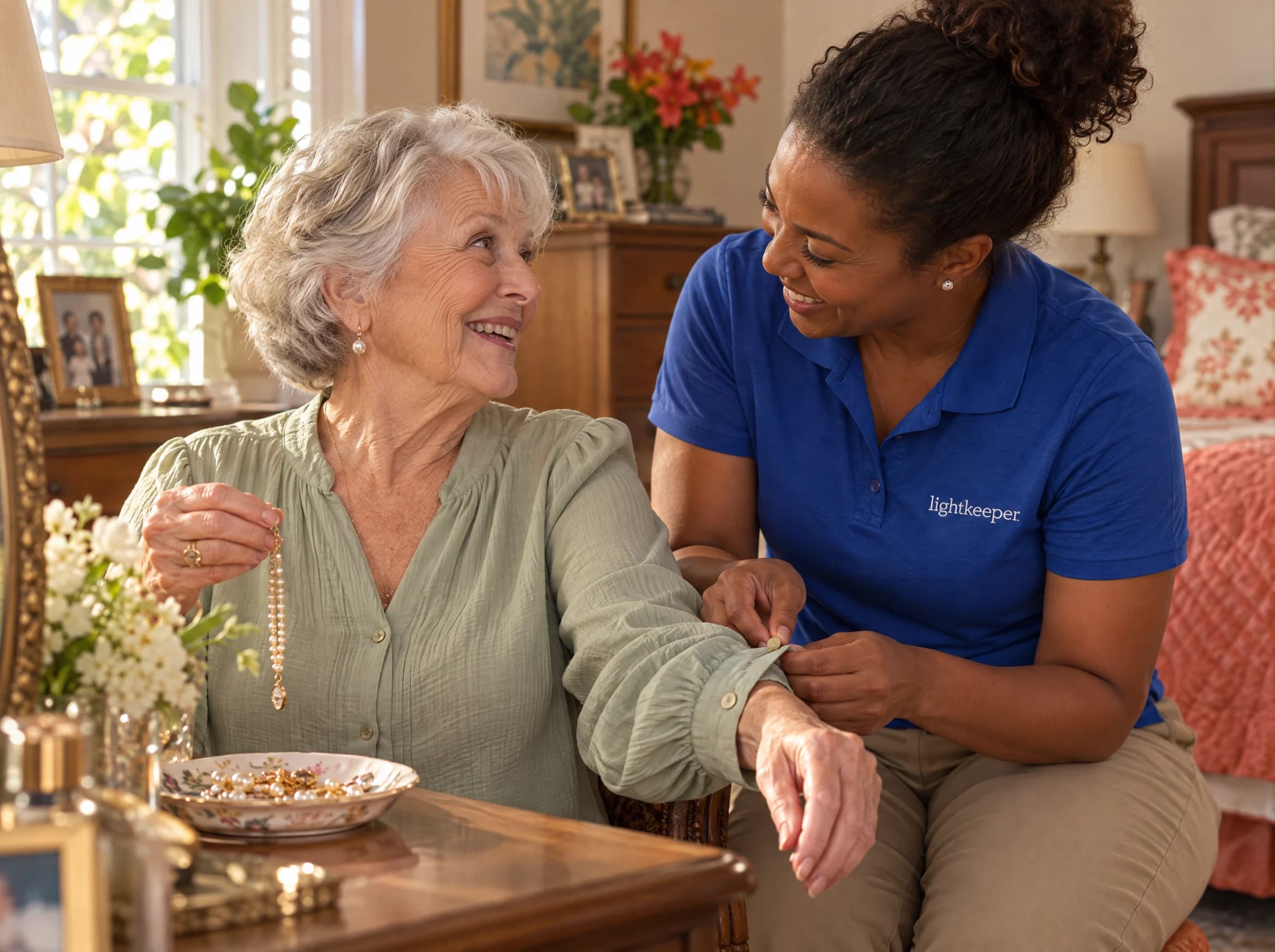 A Lightkeeper helps an older woman fasten her blouse cuff as she chooses a necklace at home